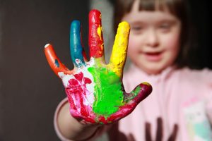 Young girl with down syndrome doing painting with her hands